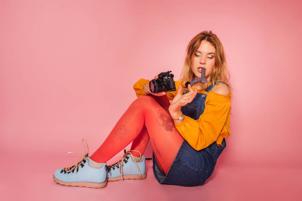 Blonde girl with retro style film camera on pink background - Foto, Imagen
