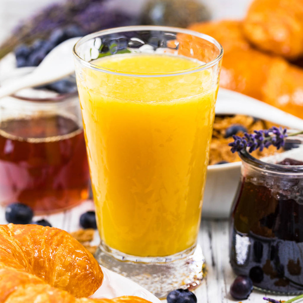 Appelsiinimehua. Mannermainen aamiainen croissanteilla, kahvilla, viljalla ja hedelmillä. Valikoiva painopiste
. - Valokuva, kuva