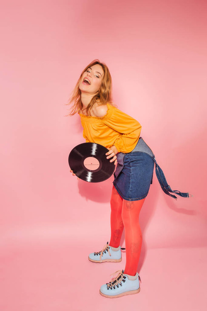 Retro style fashionable woman with vintage vinyl on pink background - 写真・画像