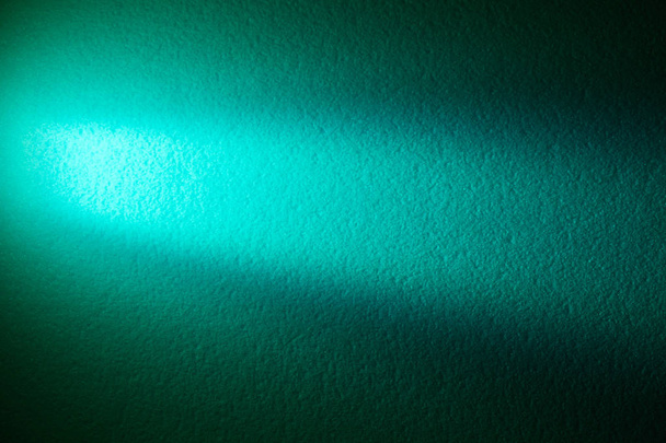 Turquoise horizontale lichtstraal op een donker groene textuur achtergrond - Foto, afbeelding