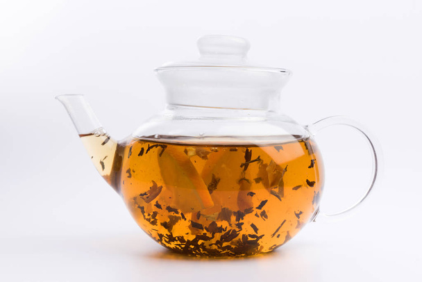 Glass teapot with black tea nad fresh orange isolated on white background - Foto, Imagen