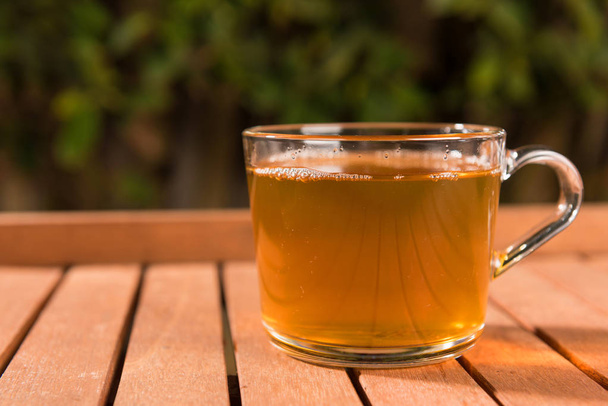Cup of green tea on wooden table outdoors - 写真・画像