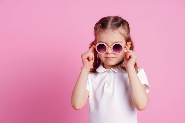 Casual 7 y.o. female in pink round sunglasses isolated on pink background - Φωτογραφία, εικόνα