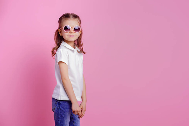 Casual 7 y.o. female in pink round sunglasses isolated on pink background - Fotó, kép
