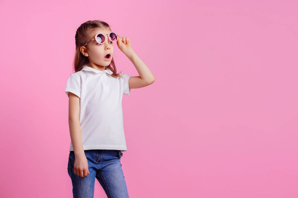 Casual 7 y.o. female in pink round sunglasses isolated on pink background - Fotó, kép