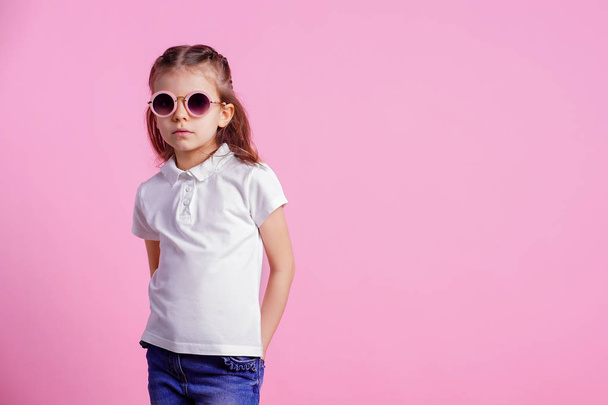 Casual 7 y.o. female in pink round sunglasses isolated on pink background - Foto, imagen