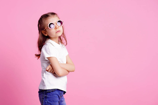 Casual 7 y.o. female in pink round sunglasses isolated on pink background - Foto, afbeelding