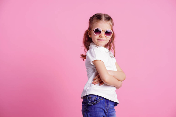 Casual 7 y.o. female in pink round sunglasses isolated on pink background - Photo, Image
