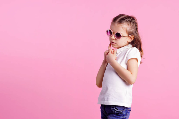 Casual 7 y.o. female in pink round sunglasses isolated on pink background - Foto, imagen