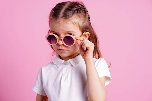 Casual 7 y.o. female in pink round sunglasses isolated on pink background - Foto, Imagem