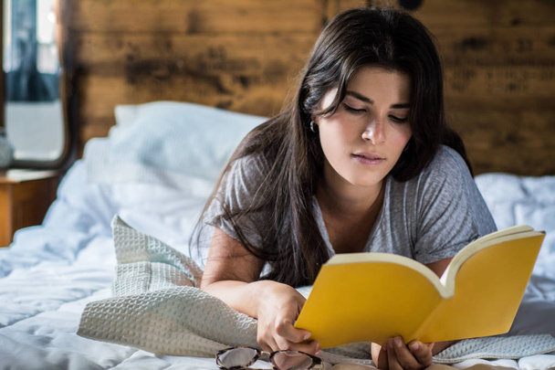 woman laying in bed and reading book - Photo, image