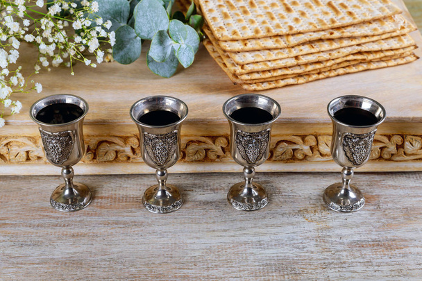 Пасхальный мацо еврейский праздничный хлеб, четыре бокала кошерного вина над деревянным столом
. - Фото, изображение