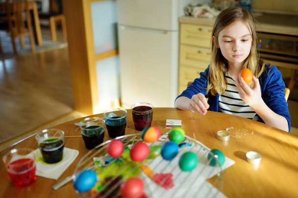 Cute young girl dyeing Easter eggs at home. Child painting colorful eggs for Easter hunt. Kid getting ready for Easter celebration. Family traditions. - Φωτογραφία, εικόνα