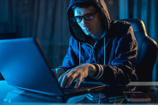 カメラで見ているフードの男性。ハッカーの攻撃とパスワードを盗んでアクセス データベース。サイバー セキュリティ - 写真・画像