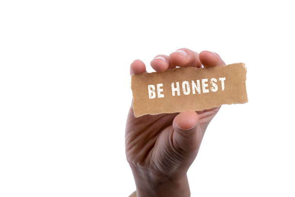 Be honest wording in hand on torn notepaper in hand - Photo, Image