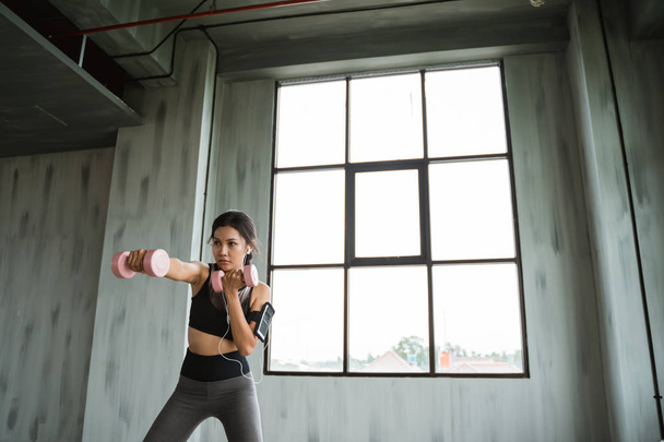 woman punching with dumbbell on her hands - Foto, Imagen