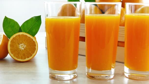 pile d'oranges fraîches dans une boîte en bois et verre de jus - Séquence, vidéo