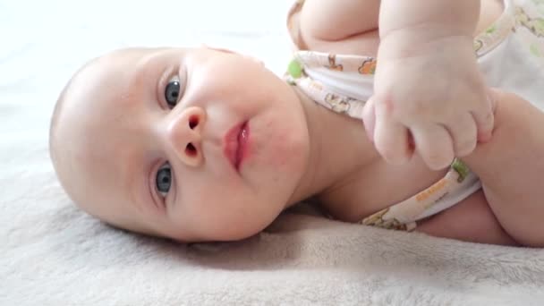 schönes Baby liegt auf dem Bett und blickt in die Kamera - Filmmaterial, Video