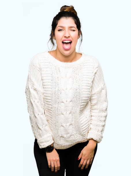 Mooie jongedame dragen winter trui winking kijken naar de camera met sexy expressie, vrolijk en blij gezicht. - Foto, afbeelding