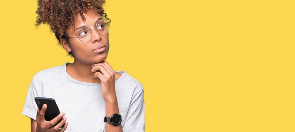Young african american woman using smartphone over isolated background serious face thinking about question, very confused idea - Foto, Bild