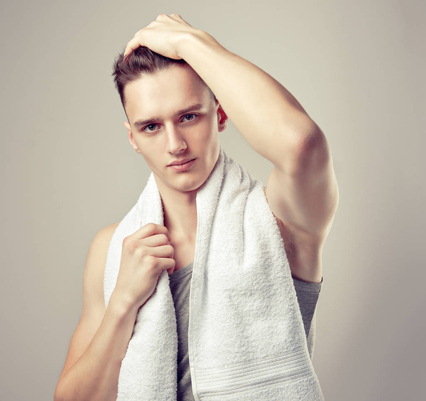 Młody atrakcyjny sportowy człowiek z ręcznikiem na ramionach po treningu. Przystojny facet z prostymi włosami przeszłości zabiegi spa lub wanny - Zdjęcie, obraz