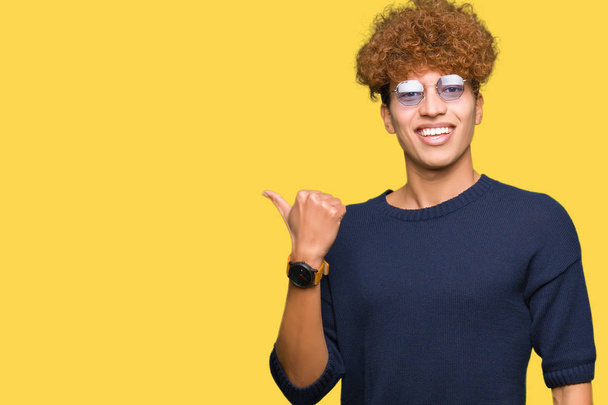 Fiatal jóképű férfi afro szemüveg, mosolygós, boldog arc, keres, és a hüvelykujj oldalán felfelé mutató. - Fotó, kép