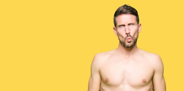 Handsome shirtless man showing nude chest making fish face with lips, crazy and comical gesture. Funny expression. - Photo, Image