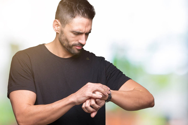 Young handsome man over isolated background Checking the time on wrist watch, relaxed and confident - 写真・画像