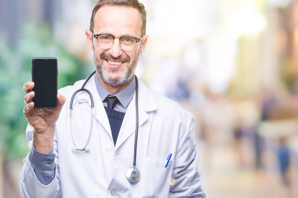 Moyen âge vieil homme médecin hoary montrant écran smartphone sur fond isolé avec un visage heureux debout et souriant avec un sourire confiant montrant les dents
 - Photo, image
