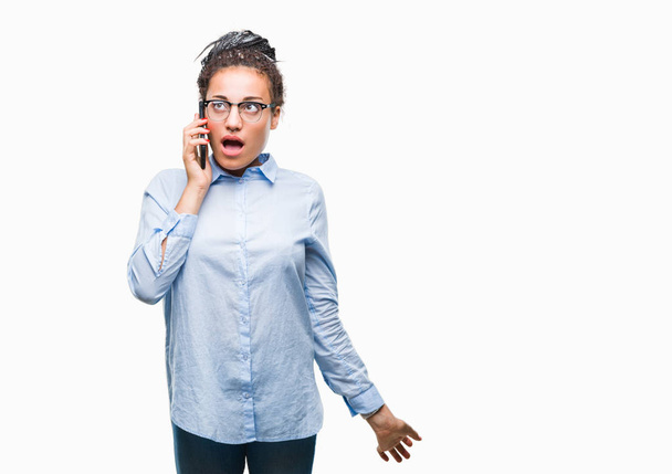 Jovem trançado cabelo afro-americano menina de negócios mostrando chamando usando smartphone sobre fundo isolado assustado em choque com um rosto surpresa, com medo e animado com expressão de medo
 - Foto, Imagem
