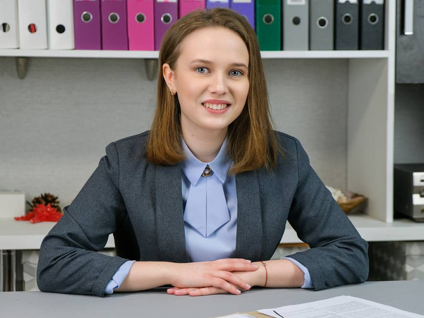 Front view Portrait of elegant manager sitting at her workplace. Business, finance and people concept: young business woman hold pages of paper. Paperworker. - 写真・画像