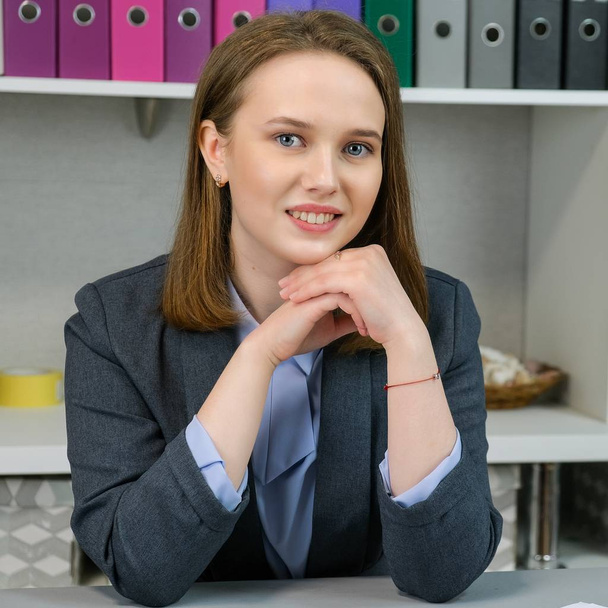 Front view Portrait of elegant manager sitting at her workplace. Business, finance and people concept: young business woman hold pages of paper. Paperworker. - Foto, Imagem
