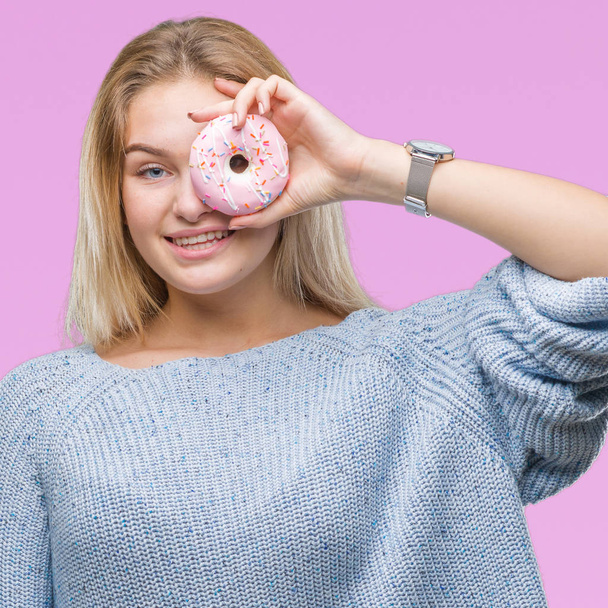 Молода біла жінка їсть солодкий пончик над ізольованим тлом з щасливим обличчям, що стоїть і посміхається з впевненою посмішкою, показуючи зуби
 - Фото, зображення