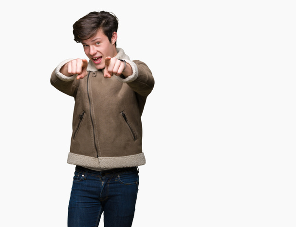Jonge knappe man dragen winterjas over geïsoleerd background Pointing aan u en de camera met de vingers, positief en vrolijk lachend - Foto, afbeelding