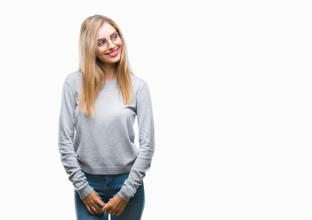 Young beautiful blonde woman wearing glasses over isolated background looking away to side with smile on face, natural expression. Laughing confident. - Foto, imagen