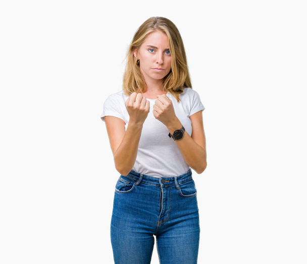 Beautiful young woman wearing casual white t-shirt over isolated background Ready to fight with fist defense gesture, angry and upset face, afraid of problem - Foto, immagini
