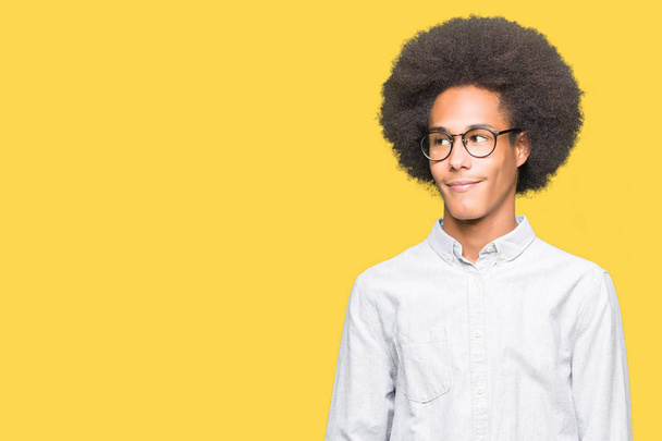 Young african american man with afro hair wearing glasses looking away to side with smile on face, natural expression. Laughing confident. - Fotografie, Obrázek