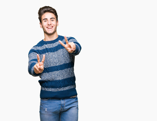 Young handsome man over isolated background smiling looking to the camera showing fingers doing victory sign. Number two. - Photo, Image