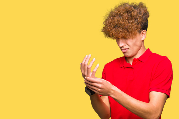 Молодий красивий чоловік з афро-волоссям у червоній футболці страждає від болю на руках і пальцях, запалення артриту
 - Фото, зображення