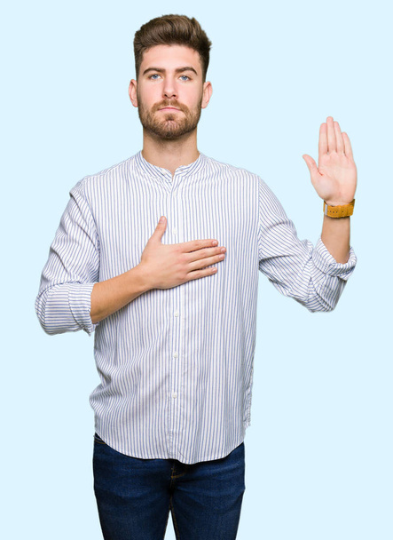 Young handsome man Swearing with hand on chest and open palm, making a loyalty promise oath - Photo, Image