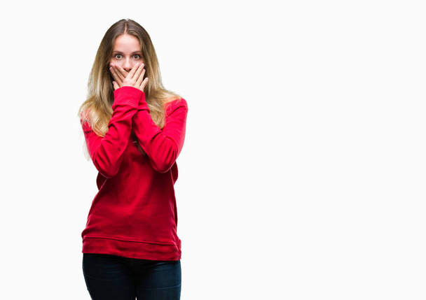 Young beautiful blonde woman wearing red sweater over isolated background shocked covering mouth with hands for mistake. Secret concept. - Фото, изображение