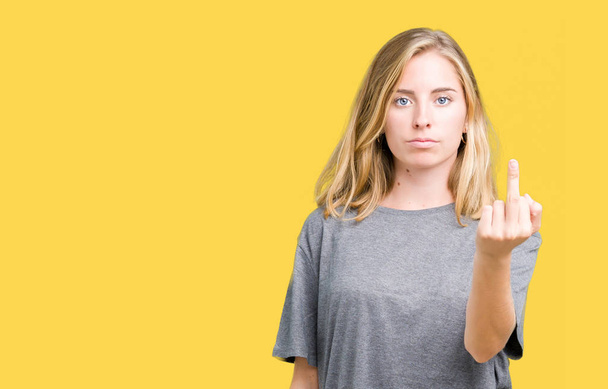 Красива молода жінка, одягнена в надлишкову футболку над ізольованим тлом, показує середній палець, неввічливий і грубий хуй вираз
 - Фото, зображення