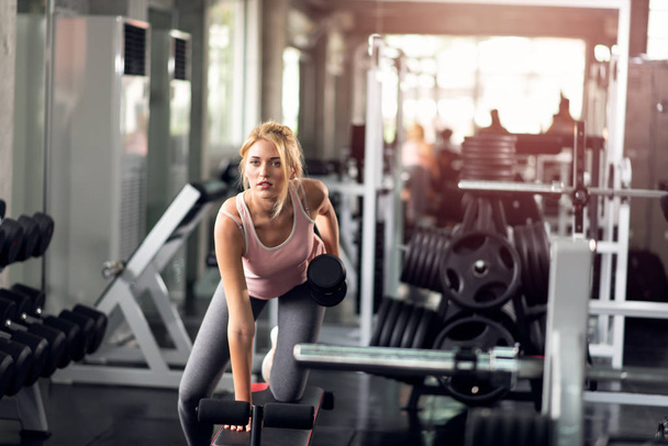 Femme forte faisant des exercices avec haltères dans la salle de gym
 - Photo, image