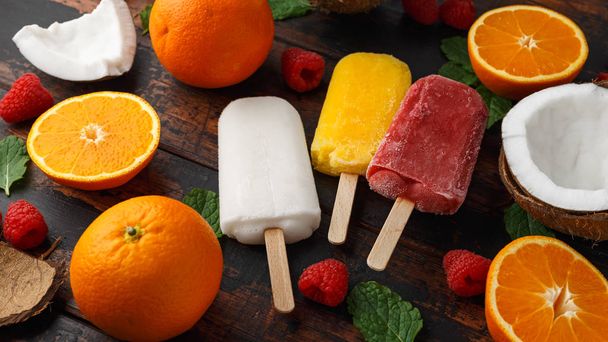 Homemade Coconut, Orange, raspberry popsicles, ice lolly, on wooden table. Summer food. - Photo, Image