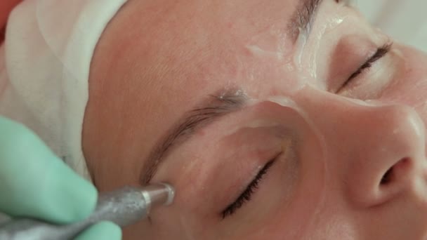 The hands of a beautician spend electrodes around the eyes of a young woman. Microcurrent massage. Beautiful girl on the procedure of cosmetology in the beauty salon. Close-up. Hardware cosmetology. - Footage, Video
