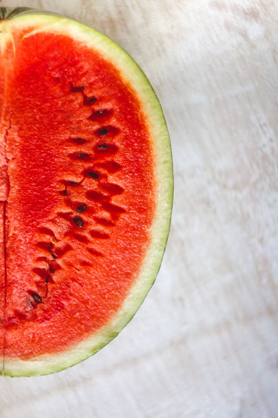 Half a juicy watermelon on a light white wooden background, clos - Fotoğraf, Görsel