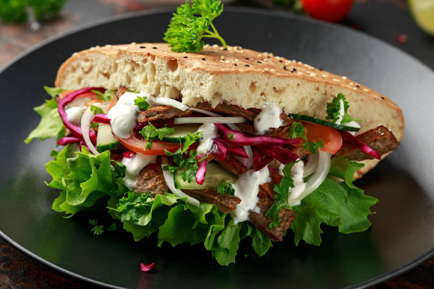 Doner kebab, carne de cordero frita con verduras y salsa de ajo en pan turco
 - Foto, imagen