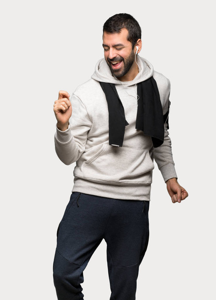 Sport man enjoy dancing while listening to music at a party over isolated grey background - Fotó, kép