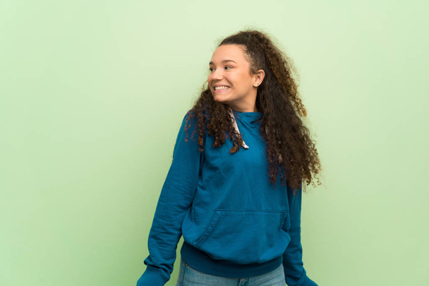 Menina adolescente feliz sobre a parede verde
 - Foto, Imagem