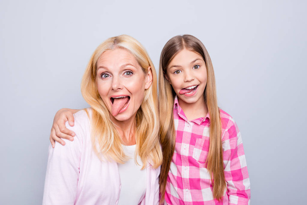 Portrait of two nice crazy cute charming attractive playful comic cheerful positive people wearing casual checkered shirt embracing showing tongue out isolated over gray pastel background - Foto, Imagem